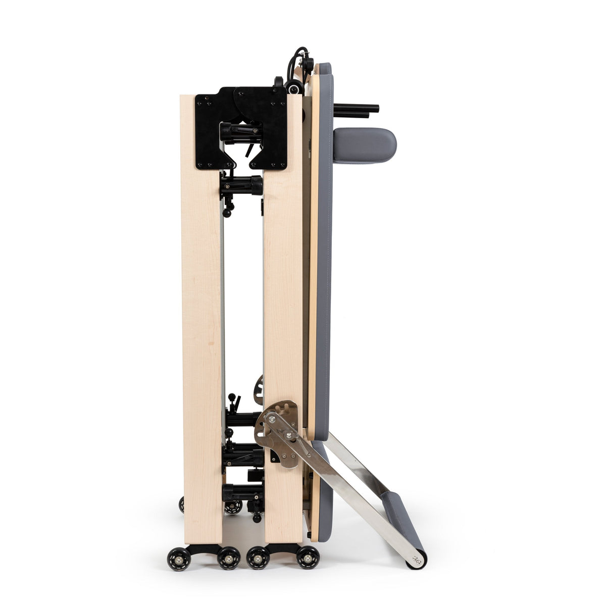 Elina Pilates Fold Reformer folded in half and standing upright on its wheels with grey upholstery