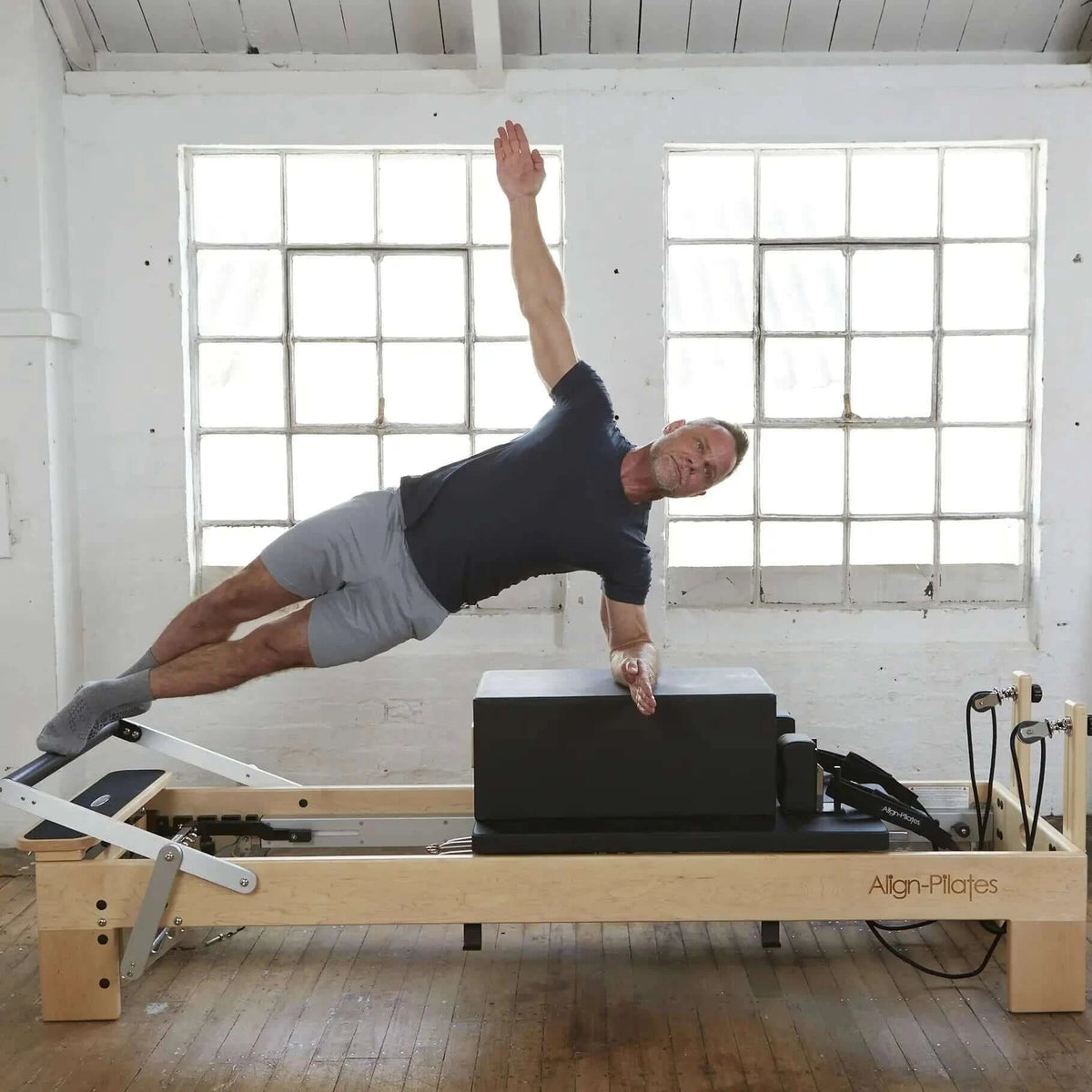 Align Pilates M8-Pro, instructor performing a side plank on the sitting box
