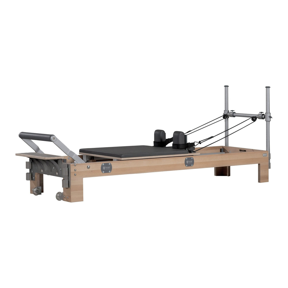 BASI Systems Reformer in beech with a dark padded carriage, padded footbar and half tower carrying the pulleys