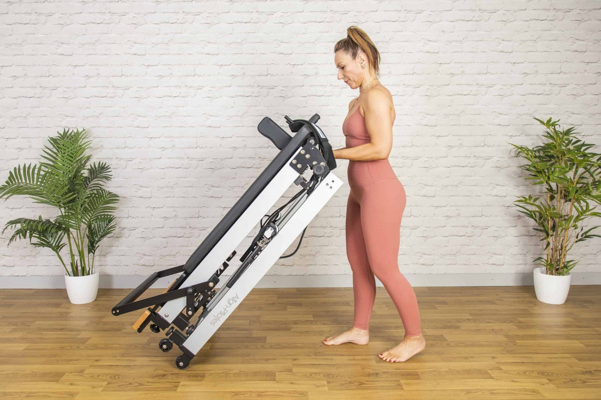 Align Pilates F3 Folding Reformer, woman lifting the frame to fold it